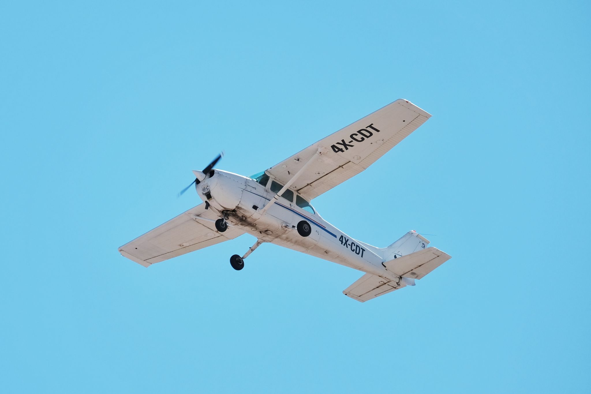 A small white airplane soaring in the clear blue sky, perfect for travel and aviation imagery.