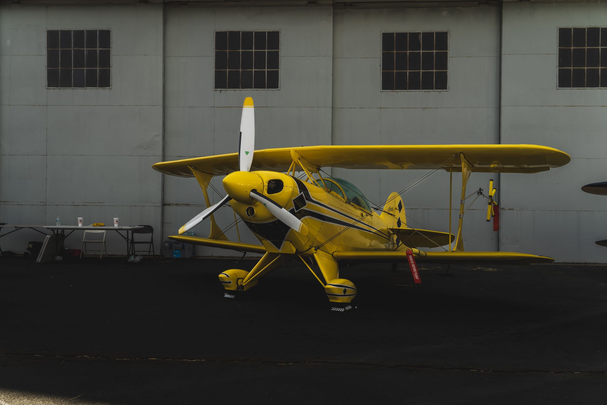 Vivid yellow biplane showcased in an aircraft hangar, ready for takeoff.